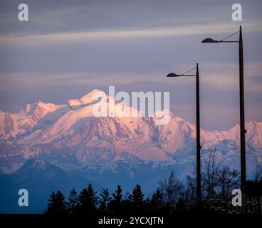 Il maestoso Monte bianco inondato dalla luce del tramonto, visto dal col de la Faucille nel Giura francese, con lampioni in primo piano. Foto Stock