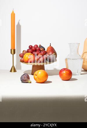 Una composizione STILL Life con frutta di stagione, noci e zucca su una tovaglia beige con luce calda Foto Stock