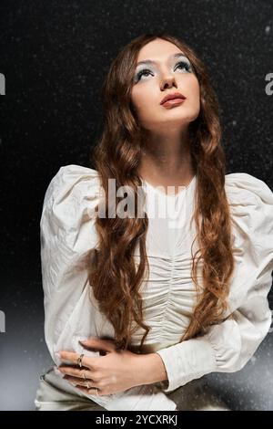 Una giovane donna in bianco guarda con attenzione verso l'alto in un ambiente sereno. Foto Stock
