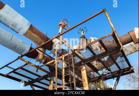 Vecchio arrugginito pipeline con valvole contro il cielo blu sullo sfondo Foto Stock