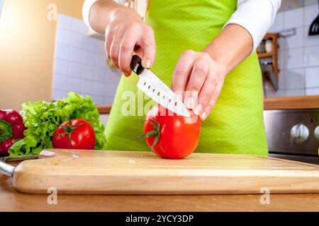 Donna con le mani in mano il taglio di pomodoro fresco su cucina Foto Stock