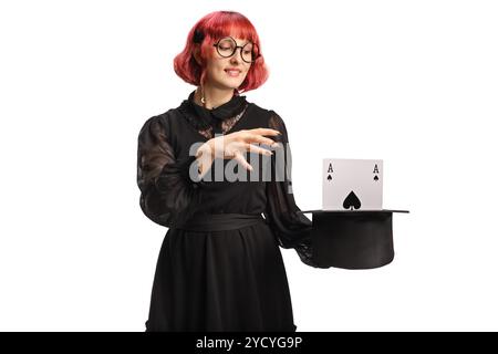 Maga con un cappello che esegue una trick magica con una carta isolata su sfondo bianco Foto Stock