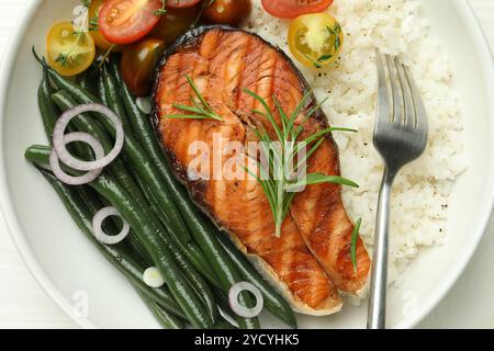 Gustosa bistecca di salmone alla griglia con riso e verdure su un tavolo bianco, vista dall'alto Foto Stock