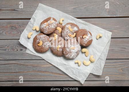 Deliziosi biscotti al cioccolato con anacardi e zucchero a velo su un tavolo di legno, vista dall'alto Foto Stock