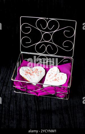 Biscotti a forma di cuore si trova in uno scrigno con panno di colore rosa. Foto Stock