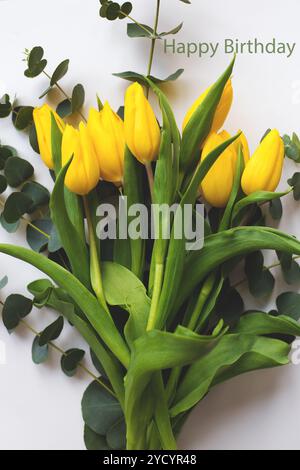 Bella tulipani gialli su un tavolo bianco, iscrizione buon compleanno Foto Stock