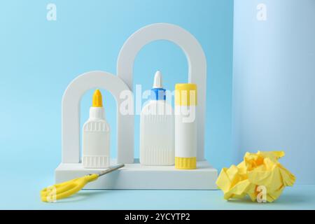 Composizione con forbici e colla su sfondo azzurro Foto Stock