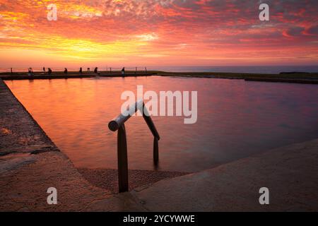 Piscina di rocce oceaniche sotto un cielo rosso ardente Foto Stock
