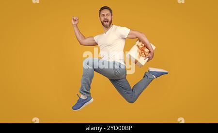 Presentare il corriere a mezz'aria. Ragazzo attivo che corre veloce con la scatola presente. Consegna di regali e regali Foto Stock