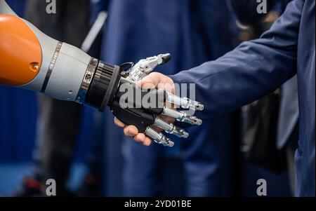 La mano di un uomo d'affari che stringono le mani con un robot androide. Il concetto di interazione umana con intelligenza artificiale. Foto Stock