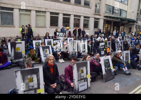 Londra, Regno Unito. 24 ottobre 2024. I manifestanti conservano foto di attivisti incarcerati e prigionieri politici durante la manifestazione. Gli attivisti hanno organizzato la mostra di protesta dei prigionieri politici liberi al di fuori del Ministero della giustizia, invitando il procuratore generale a liberare gli attivisti per il clima e altri manifestanti attualmente nelle prigioni britanniche. I manifestanti che hanno partecipato alla mostra hanno bloccato la strada fuori dal MOJ con foto di attivisti in carcere e di altri prigionieri politici. Credito: SOPA Images Limited/Alamy Live News Foto Stock