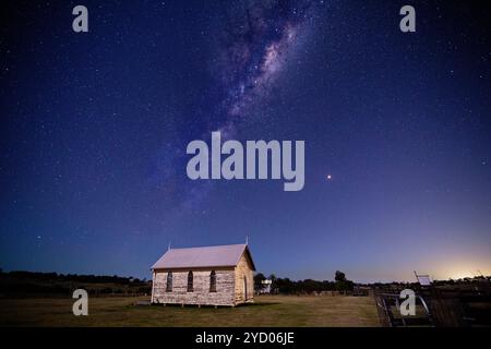 Cielo stellato dell'universo Mikly Way sopra una vecchia cappella in legno rustica e un campo rurale in Australia Foto Stock