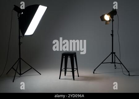 Studio fotografico con apparecchiature di illuminazione. schema di illuminazione e sedia. Il concetto di selezione e fusione. Annuncio di assunzione di lavoro. Foto Stock