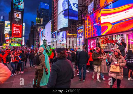 Vivace scena di turisti a Times Square, New York City, con cartelloni luminosi e artisti vestiti come la Statua della libertà. New York. STATI UNITI. Foto Stock