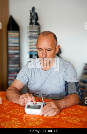 L'uomo misura la propria pressione sanguigna a casa da solo Foto Stock