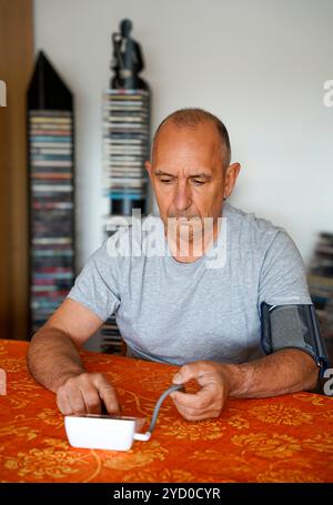 L'uomo misura la propria pressione sanguigna a casa da solo Foto Stock