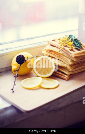 Cialde viennesi piene e limone a fette. Affettare il limone su una tavola di legno. La frutta viene tritata. Limone acido. Foto Stock