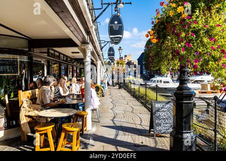 Persone che cenano all'aperto presso ristoranti e caffetterie a St Katharine Docks, Londra, Inghilterra Foto Stock