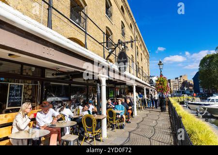 Persone che cenano all'aperto presso ristoranti e caffetterie a St Katharine Docks, Londra, Inghilterra Foto Stock