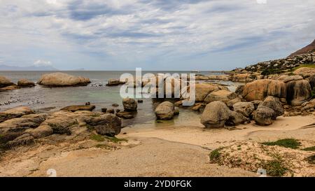 paesaggio di grandi massi di granito che creano piscine di roccia d'acqua poco profonde presso la spiaggia di boulder vicino a città del capo, accanto alla colonia di pinguini africani Foto Stock