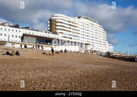 Una giornata invernale a St. Leonards-on-Sea, Hastings, Regno Unito, con persone sulla spiaggia di ciottoli vicino all'iconico edificio Art Deco Marine Court sotto un cielo freddo. Foto Stock