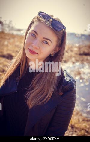 La ragazza con i capelli biondi di passeggiate nel parco in primavera. Una ragazza con i capelli biondi. Ragazza giovane bella e sottile Foto Stock