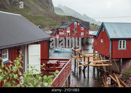 Cottage rossi arroccati su palafitte accanto a un tranquillo lago creano un pittoresco villaggio di pescatori a Lofoten, Norvegia, invitanti attività di svago ed explora Foto Stock