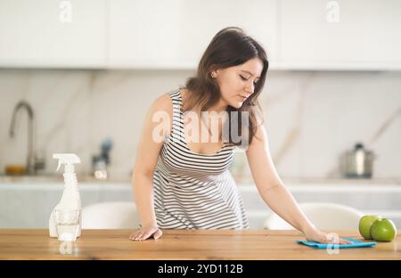 Giovane donna che pulisce il tavolo con lo straccio Foto Stock