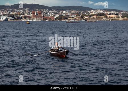 Oslo, Norvegia - 18 agosto 2018: Uomo che canta un salto sul fiordo di Oslo con Town House sullo sfondo Foto Stock