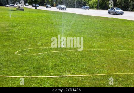 Irrigatore a spruzzo per innaffiare il prato in città Foto Stock