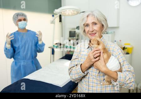 Donna sorridente che tiene con la pancia fasciata dopo un intervento chirurgico riuscito Foto Stock