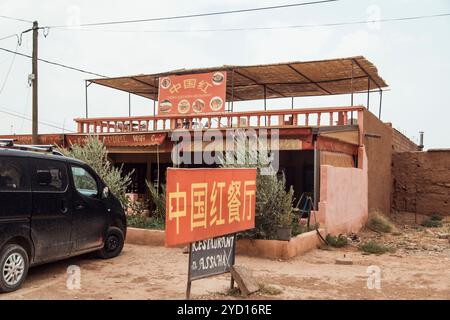 Un'auto di lusso per famiglie è parcheggiata accanto a un vivace ristorante marocchino con un'area salotto all'aperto. La facciata dell'edificio mostra una caratteristica caratteristica caratteristica Foto Stock