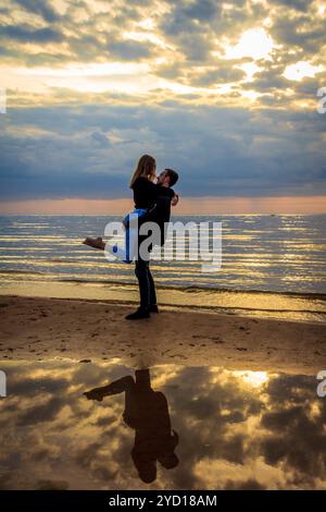 Il tizio con la ragazza al tramonto sul mare. Il Golfo di Finlandia. Tramonto sul mare. Sera d'estate. Storia d'amore. Una giovane coppia. Russia, Foto Stock