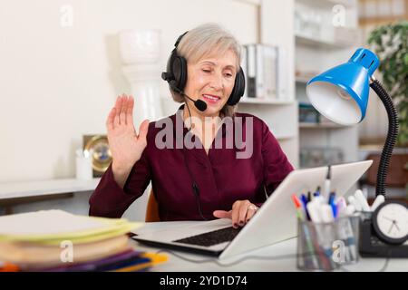 Donna in auricolari che lavorano in ufficio Foto Stock