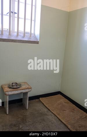 Cella tipica su Robben Island con tappetino, panca, tazza e piatto Foto Stock