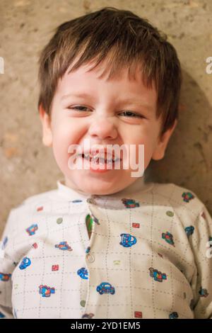 Ritratto di un ragazzo sullo sfondo di un muro di cemento. Il ragazzo sorride. Il ragazzo sta guardando la telecamera. Foto Stock