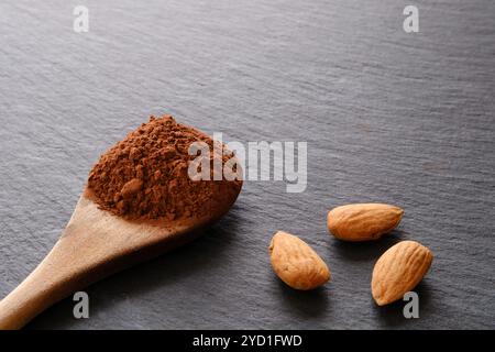 Cucchiaio di cacao in polvere e mandorle sullo sfondo dell'ardesia Foto Stock