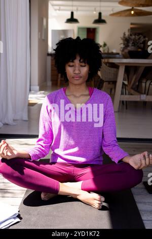 donna che meditava sul tappetino da yoga a casa, trovando pace interiore Foto Stock