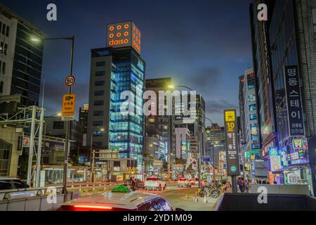Strada trafficata della città con un grande edificio sullo sfondo. Ci sono molte auto e motociclette sulla strada Foto Stock