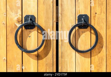 Massiccio cancello in legno con manopole in metallo Foto Stock