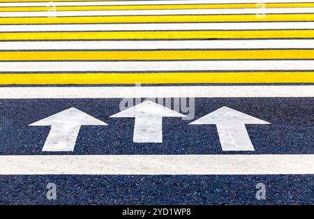 Attraversamento pedonale con frecce, strisce bianche e gialle Foto Stock