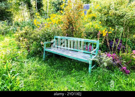 Vecchia panchina di legno nel giardino dei fiori Foto Stock