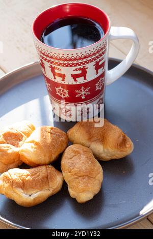 Caffè in una tazza e croissant su un piatto. Cibo e bevande. Piastra su fondo di legno. Foto Stock