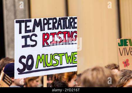 Un segno a mano legge la temperatura è in aumento, così dobbiamo essere noi su una strada di città come manifestanti ecologico marzo per salvare l'ambiente. Foto Stock