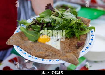 Cibi preparati al momento è visto da vicino su una piastra durante un outdoor fiera alimentare, insalata fresca con uovo fritto servito in un wrap come un pasto sano. Foto Stock