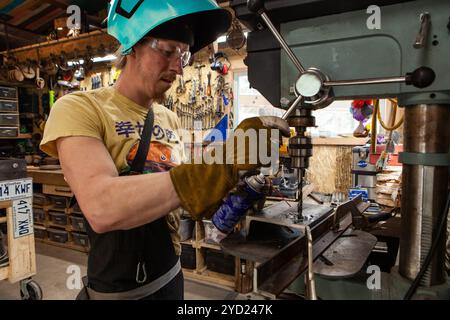 Il commerciante utilizza un trapano a piedistallo in garage Foto Stock