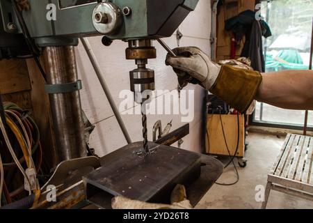 Il fabbro utilizza una pressa per trapano in garage Foto Stock