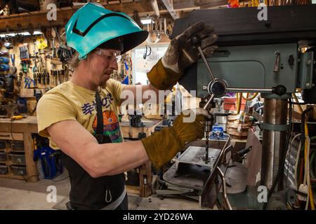 Uomo che utilizza un trapano a colonna all'interno dell'officina Foto Stock
