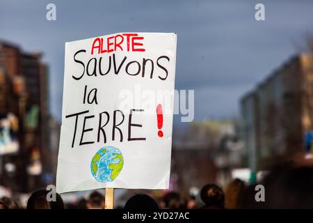 Una vista ingrandita di un francese della lettura del segno di avviso, salvare il pianeta. Tenuto da un attivista ecologico durante una strada pacifica protesta. Foto Stock