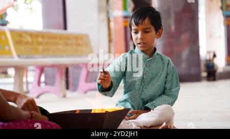 Una famiglia indù si riunisce intorno a un fuoco sacro per Yagya durante una festa. I rituali Havan e pooja includono offerte e mantra vedici Foto Stock